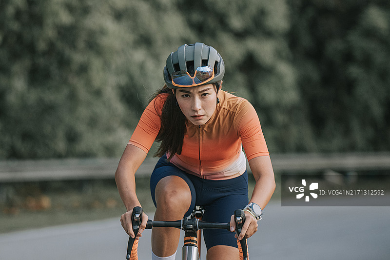 骑自行车的亚洲华人运动女性：在路上锻炼的健美女性，进行耐力和有氧运动图片素材