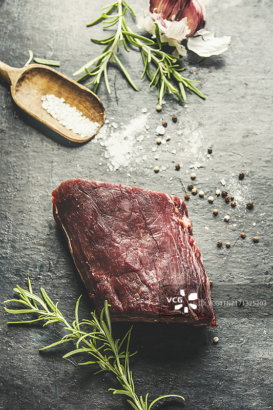 乡村背景下的生牛里脊，配有盐和新鲜调味料图片素材