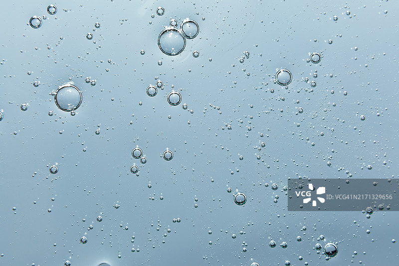 浅蓝色背景上的透明芦荟凝胶或保湿乳液气泡纹理，草本化妆品健康护肤概念图片素材