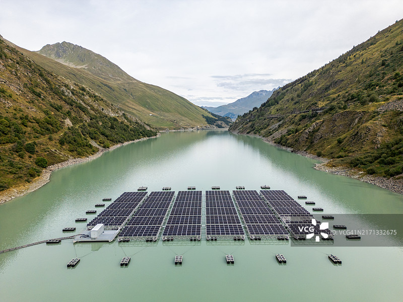 平静山间湖上的漂浮太阳能电池板阵列图片素材
