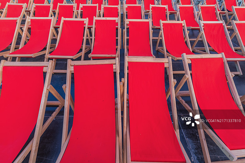 沙滩上排列整齐的红色帆布床或椅子图片素材
