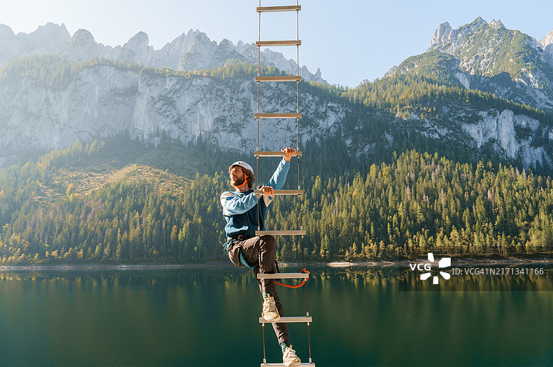 男人在奥地利戈绍萨湖上方攀岩，欣赏美丽风景图片素材