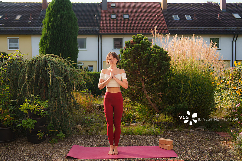 女人在阳光明媚的早晨在后院做瑜伽图片素材