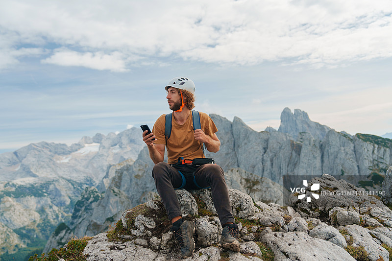 男人登山后在山顶使用智能手机图片素材