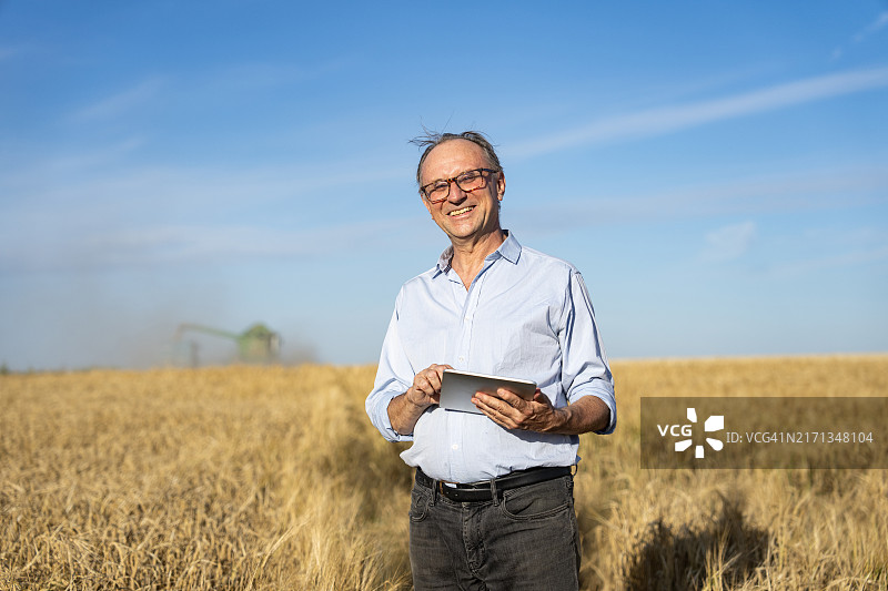 农艺师在麦田进行作物评估，背景是收割机图片素材