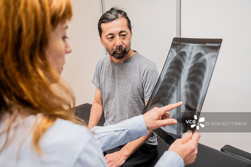 女医生在诊室向患者展示体检报告图片素材