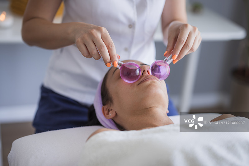 女人做冰球脸部按摩，特写图片素材