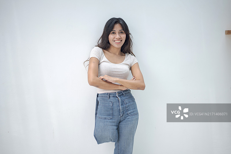 微笑的残疾截肢妇女穿着休闲服装，在白色背景下交叉双臂站立图片素材