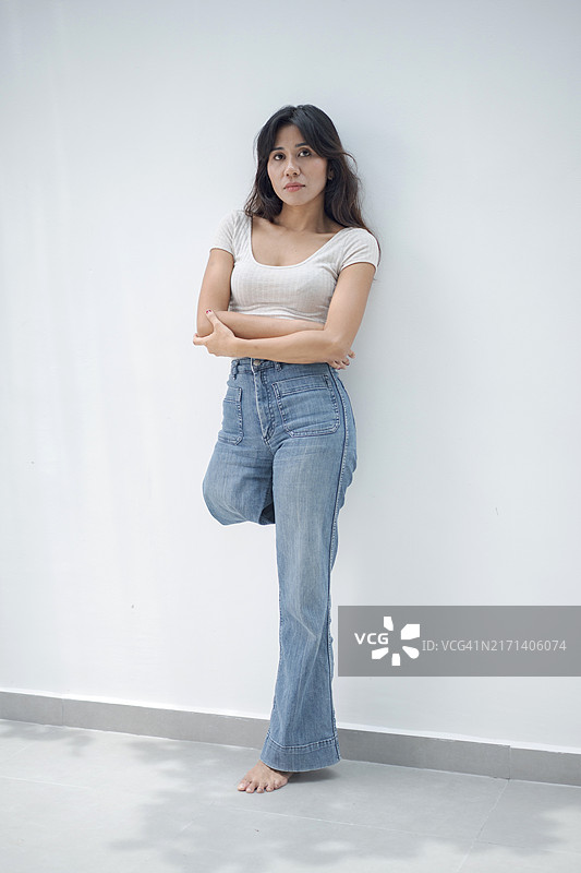 微笑的残疾截肢妇女穿着休闲服装，在白色背景下交叉双臂站立图片素材