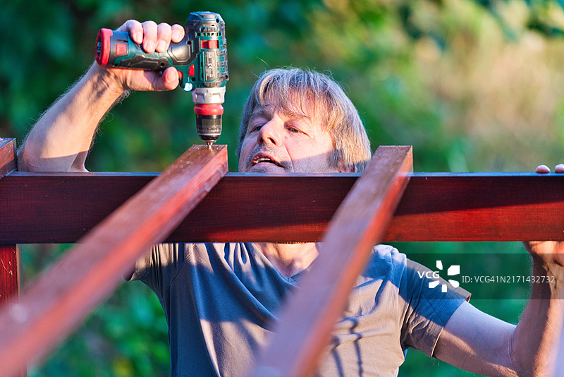 修理后院木制凉棚的中年男人图片素材