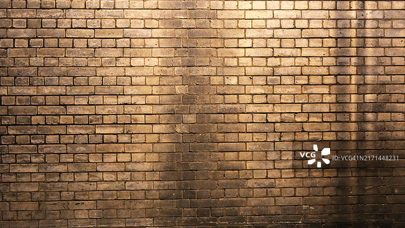 特写：伦敦饱经风霜的棕色砖墙，夜间在街灯下拍摄图片素材