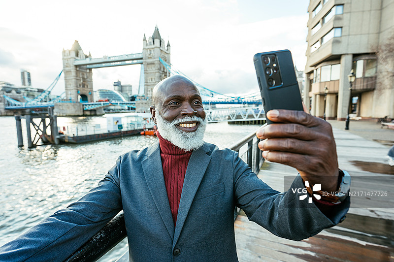 在英国伦敦旅游，在塔桥附近拍照和发送照片信息的年长黑人游客图片素材