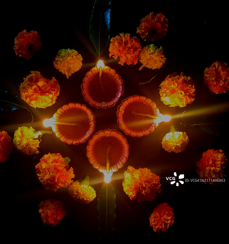 排灯节：黑色背景下的点燃泥土油灯、万寿菊花、芒果叶图片素材