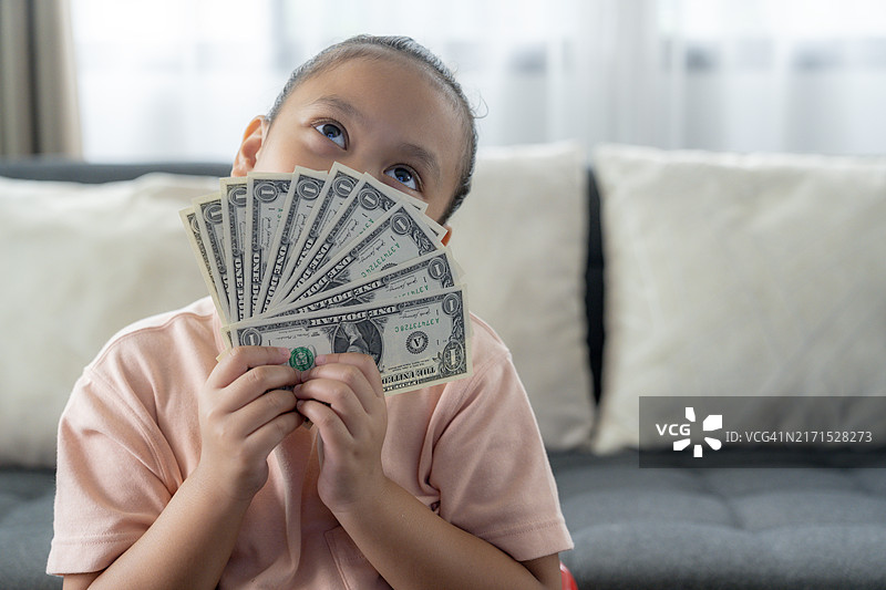 投资理念：手持大量钞票的小女孩图片素材