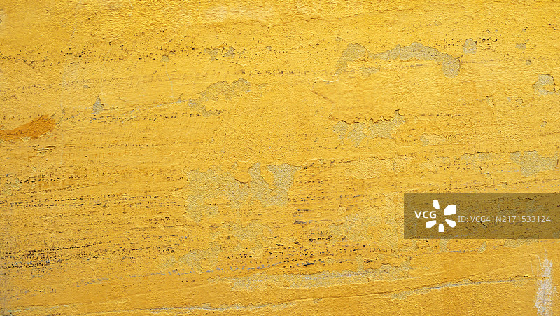 满是剥落的黄色油漆的混凝土墙壁,整体画面。粗糙的纹理。阳光。自然色彩。葡萄牙,波尔图。图片素材