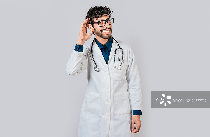 微笑的医生听着谣言。年轻医生捂着耳朵微笑，微笑的医生伸出手图片素材