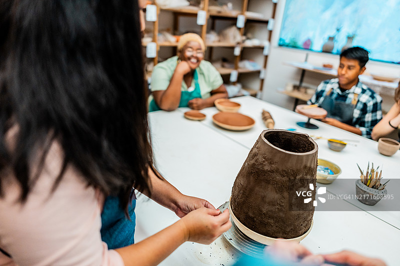 陶艺工作坊中陶工正在捏制陶土的特写镜头图片素材