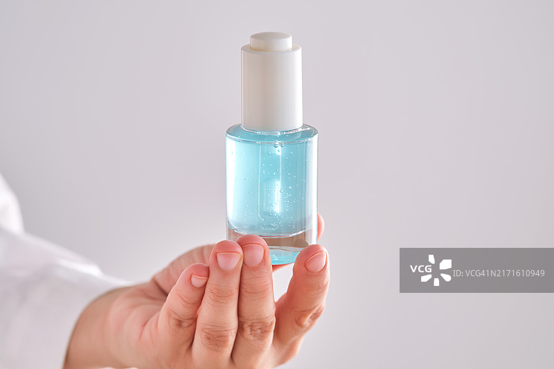 穿长袍的女人手中拿着带滴管的蓝色精华液图片素材