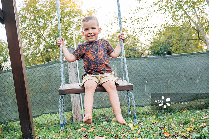 在院子里荡秋千的快乐赤脚儿童图片素材