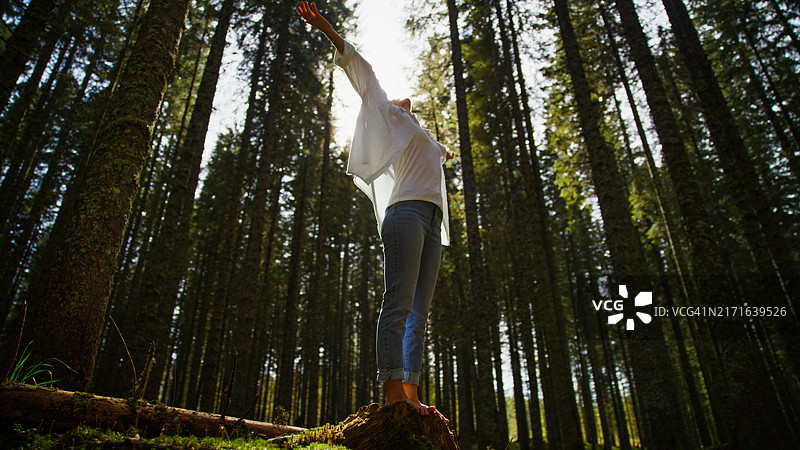 女人在森林中的树桩上保持平衡图片素材