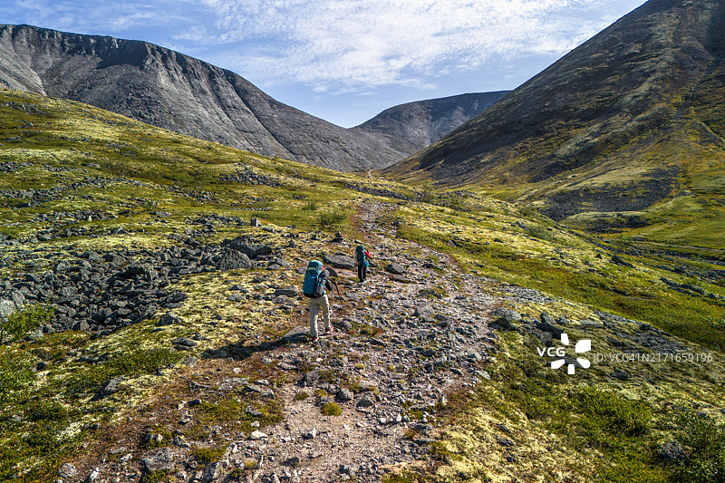 一位女士带着孩子在美丽北方山区小路上行走的航拍图片素材