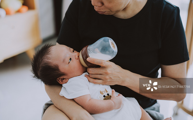年轻的亚洲妈妈用奶瓶喂宝宝图片素材