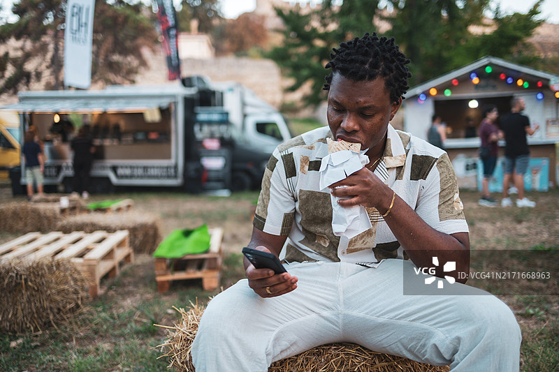 在户外餐车美食节享受街头美食的男人图片素材