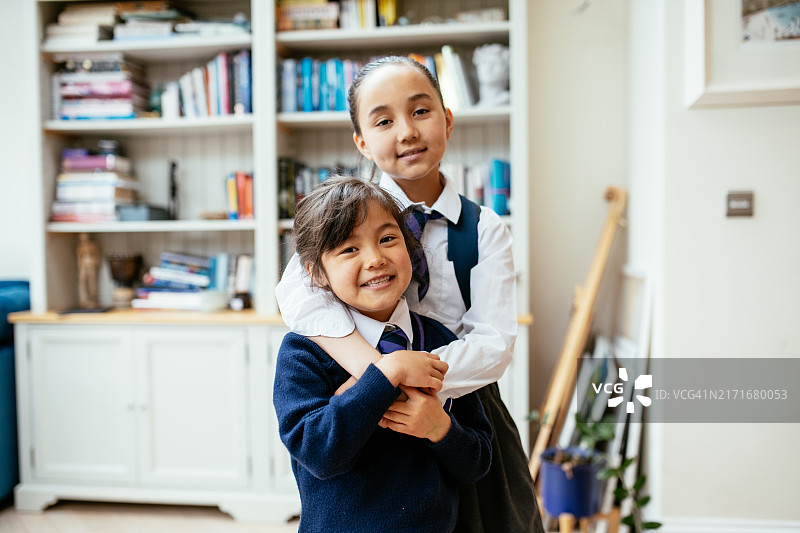 穿着校服看向镜头拥抱的亚洲女学生们，姐姐背着书包图片素材