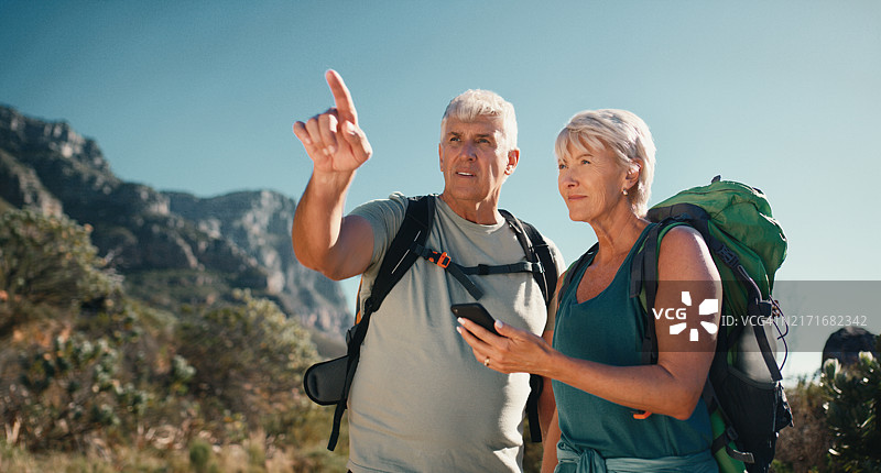 老年夫妇在户外徒步旅行，使用手机地图导航图片素材