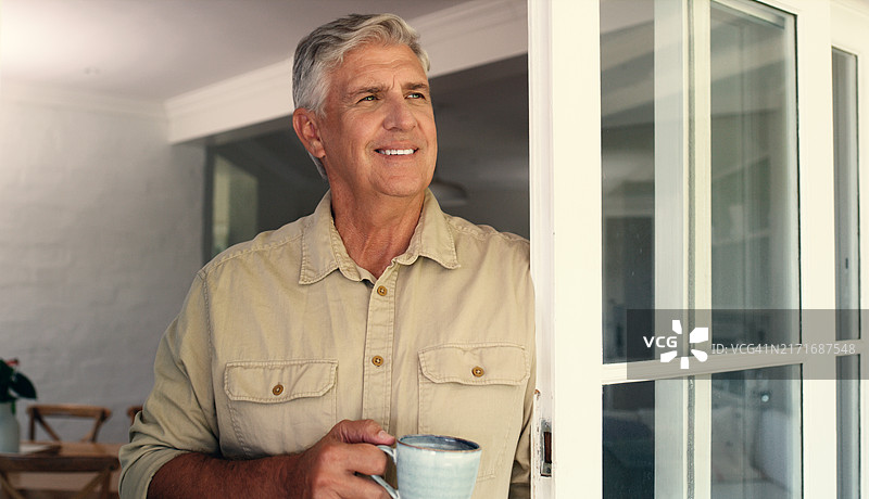 年长的男人，在窗边喝咖啡时快乐地思考，退休后的放松和舒适。退休建筑师，在家中喝茶时的自豪和微笑，和平和终身成就与愉快的过去回忆图片素材