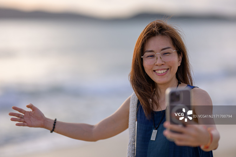 金色阳光：游客在海边享受日落自拍图片素材