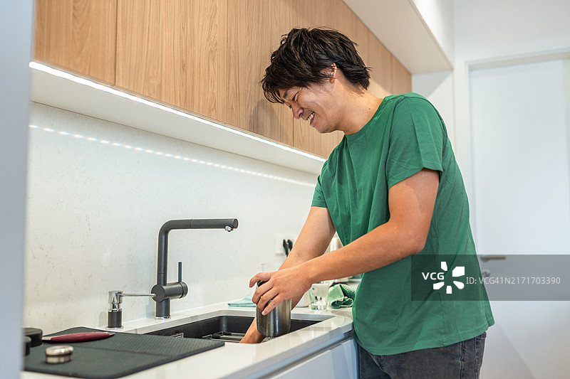 亚洲男性在家厨房专心洗碗图片素材