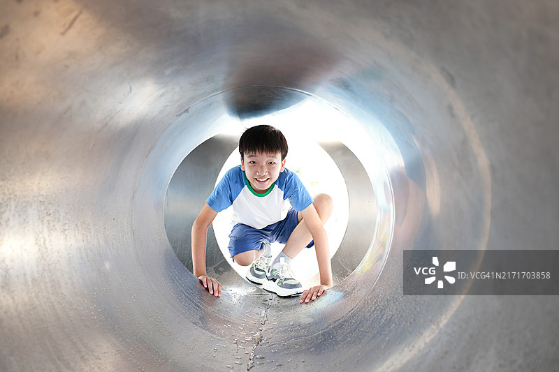 男孩在公园的管道里玩耍图片素材