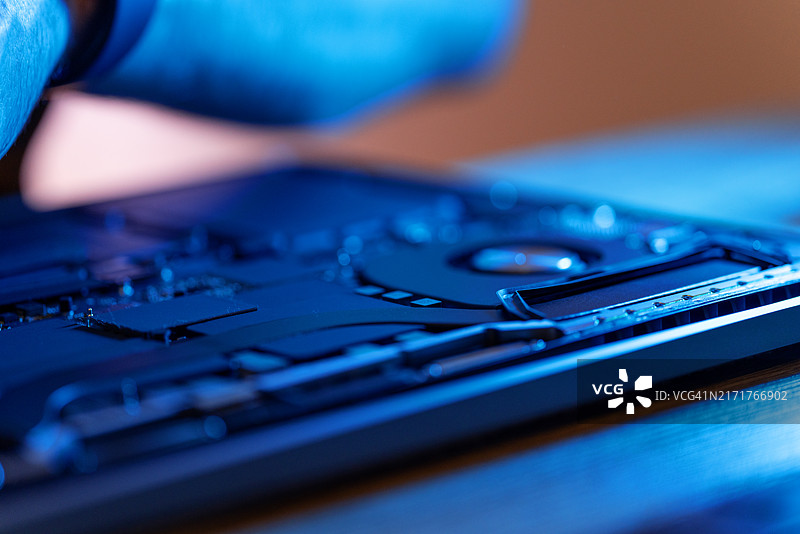 男人在柔和的光线下仔细检查笔记本电脑的内部组件并清洁灰尘图片素材