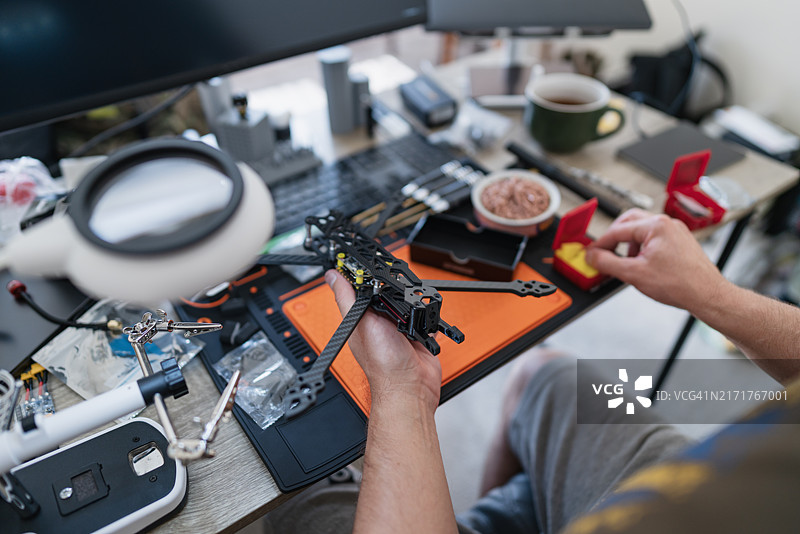 工程师在堆满工具和组件的工作区组装FPV无人机图片素材