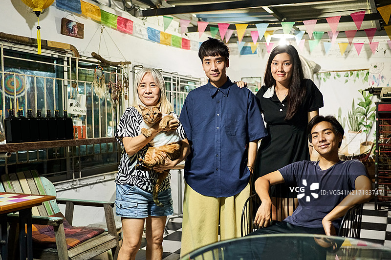 年长的民宿店主抱着虎斑猫和年轻客人们。图片素材