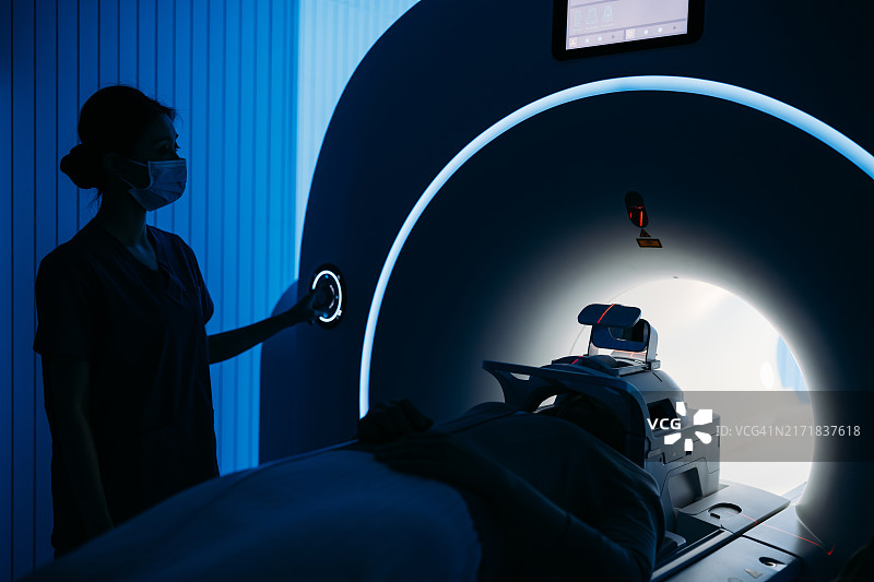 医院里，病人躺在医疗扫描仪内，护士正在操作机器图片素材