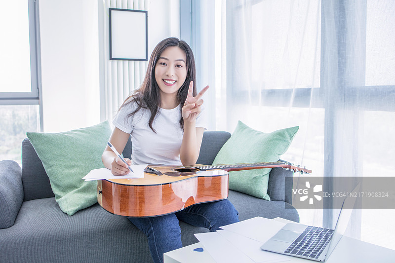 亚洲女性在家弹吉他并创作歌词图片素材