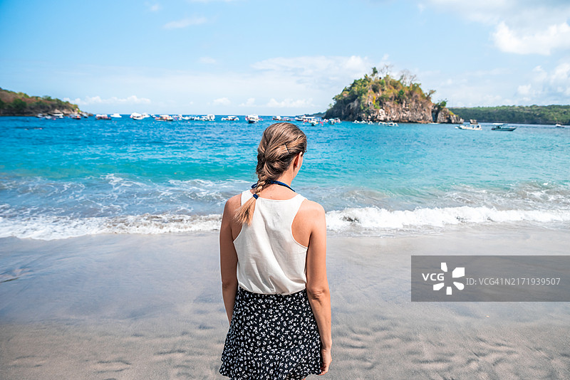 年轻女子欣赏巴厘岛水晶湾海滩清澈的海水图片素材