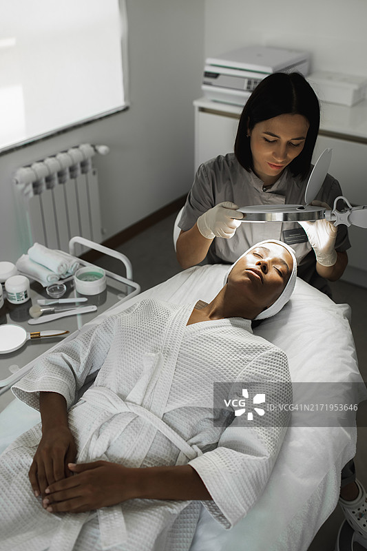 女美容师用放大镜观察顾客的皮肤图片素材