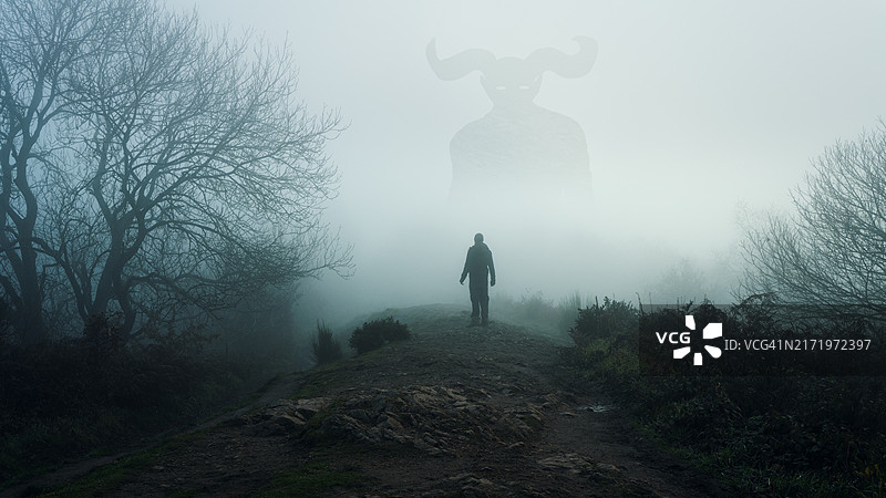 一个人仰望着从雾中出现的巨大恐怖带角神灵图片素材