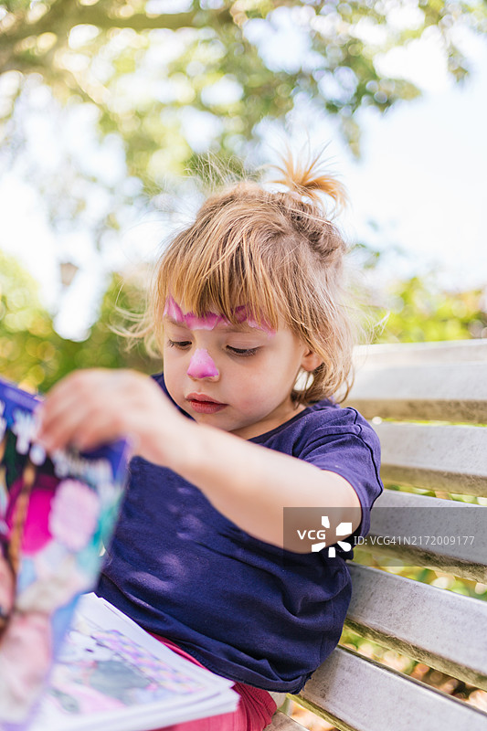 可爱的小女孩在阳光明媚的公园里读书图片素材