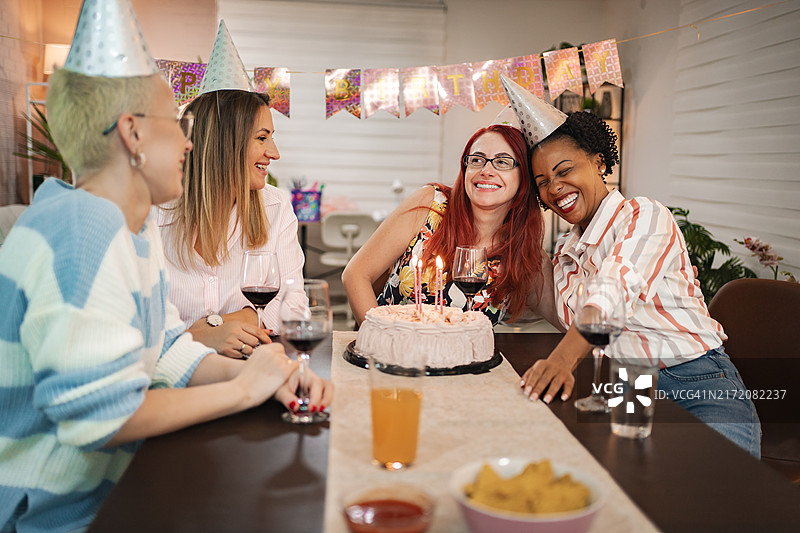 朋友们在舒适的聚会上庆祝40岁生日，充满欢笑和蛋糕图片素材