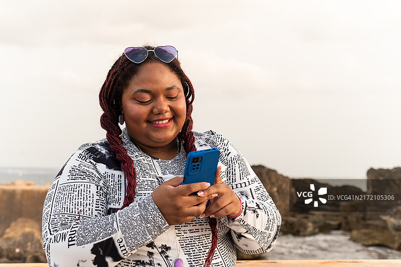 站在海边的拉丁超重女性正在使用手机图片素材