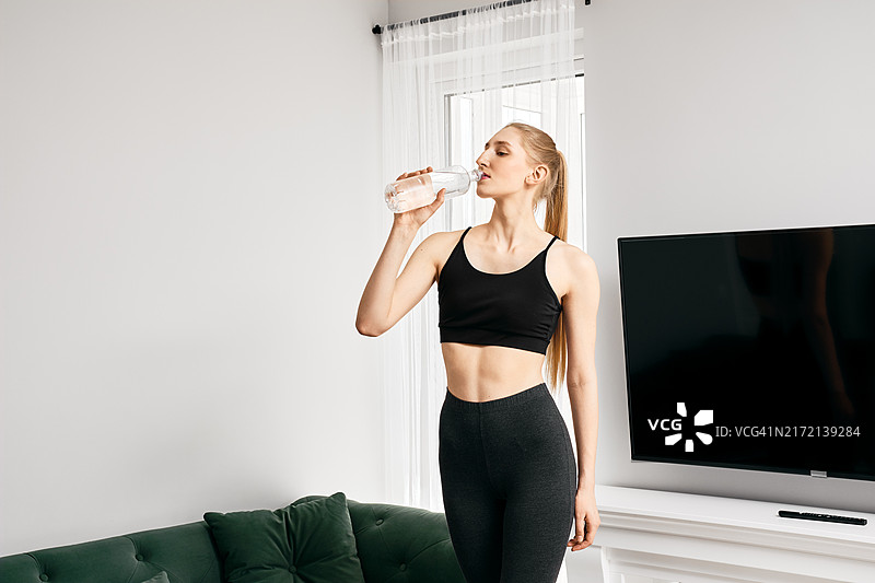 年轻女子在家运动时喝水图片素材