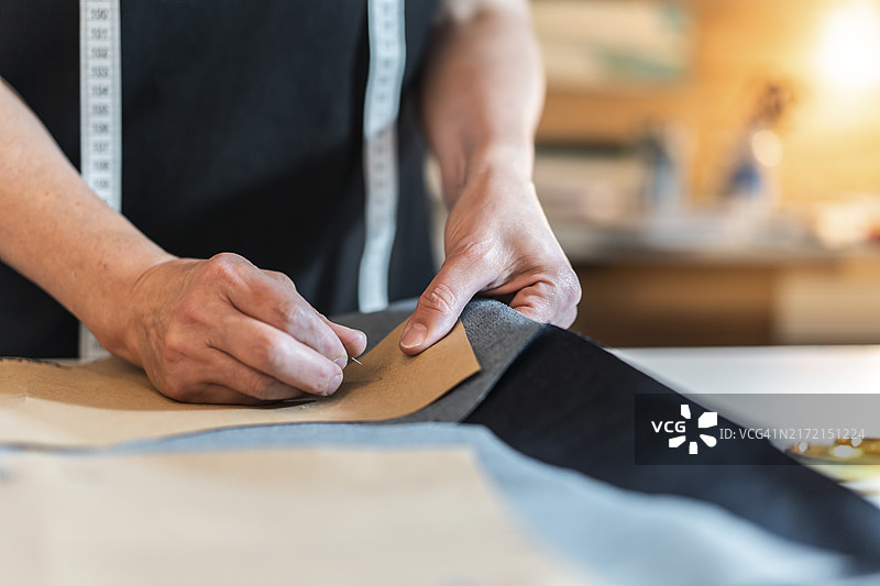 时装设计师将大头针插入图案和面料图片素材