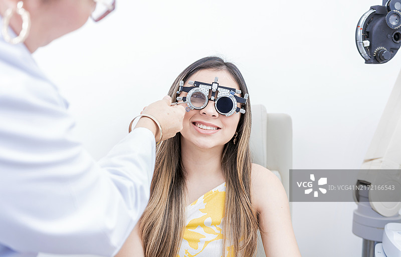 微笑的病人与验光师试戴镜架。验光师仔细检查戴着试戴镜架的病人图片素材