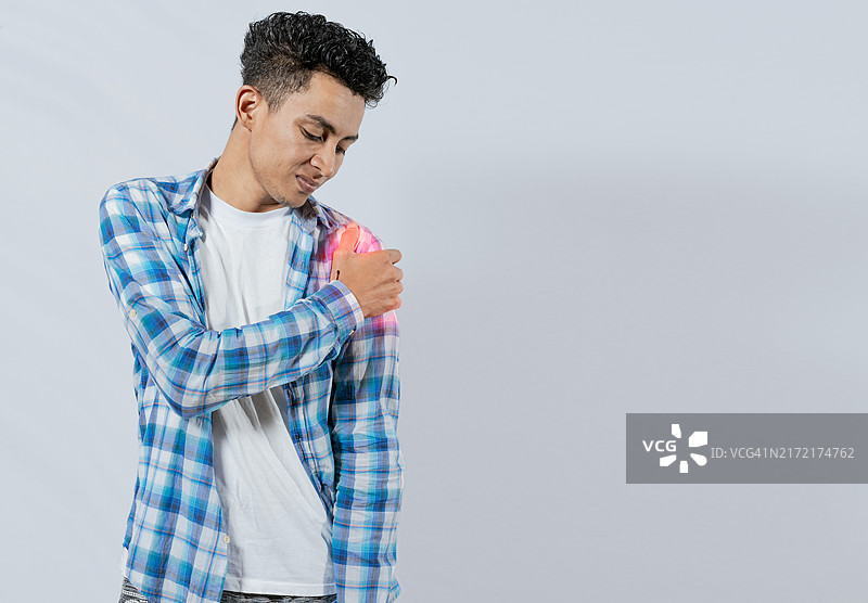 白色背景下肩部疼痛的年轻男人，肩臂疼痛概念图片素材