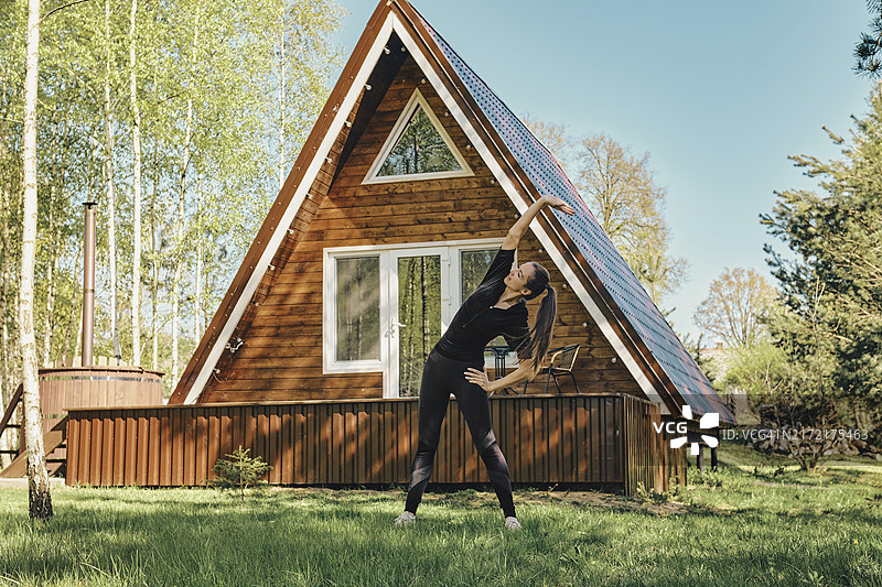 活力女人在草坪上做身体拉伸运动图片素材