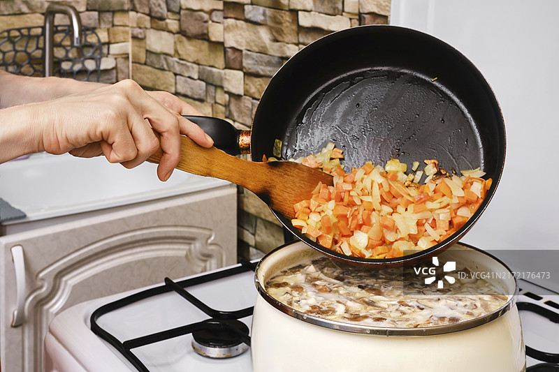 女人在汤里加入炸胡萝卜、洋葱和大蒜图片素材